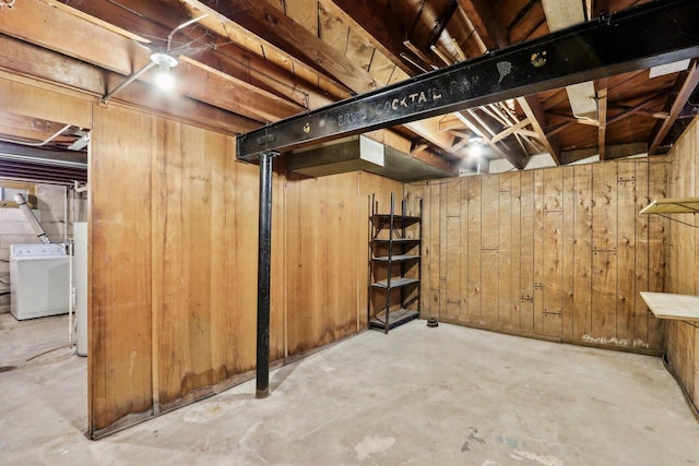 basement with wooden walls, washer / dryer, and water heater