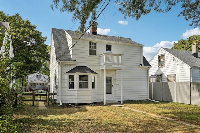 rear view of house with a balcony and a yard