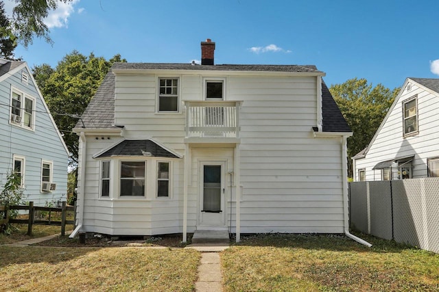 back of house with a lawn and a balcony