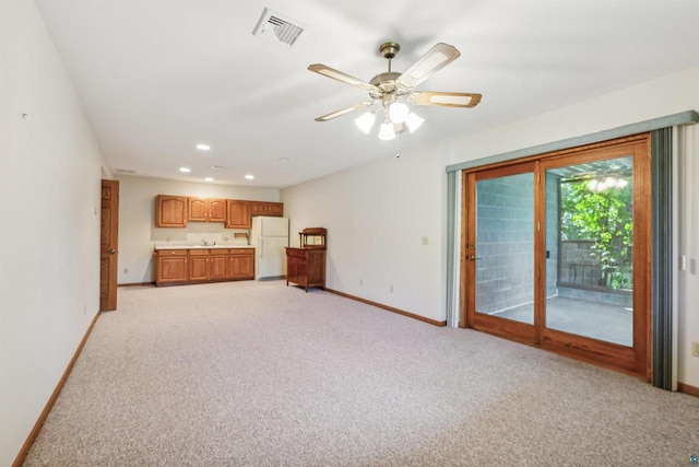 unfurnished living room featuring ceiling fan and light colored carpet