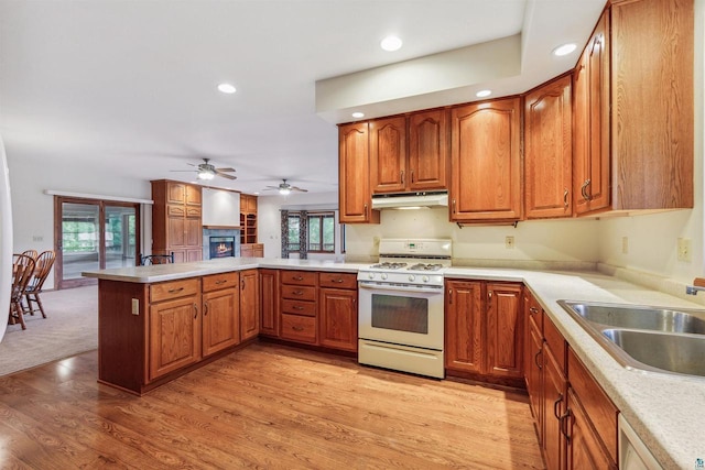 kitchen featuring ceiling fan, sink, gas range gas stove, kitchen peninsula, and light hardwood / wood-style floors