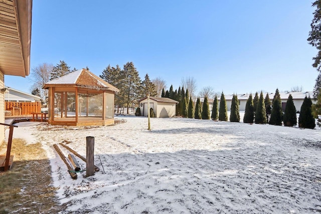 yard layered in snow featuring a shed and a gazebo