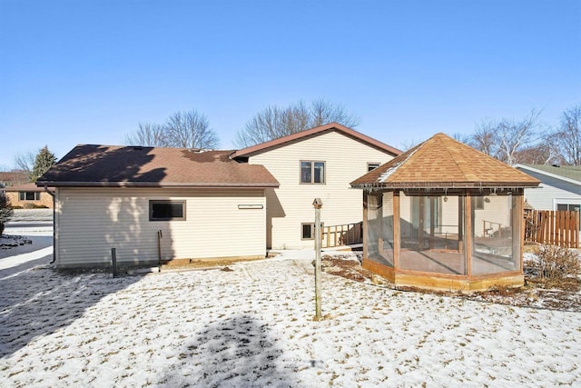 snow covered back of property featuring a gazebo and a sunroom