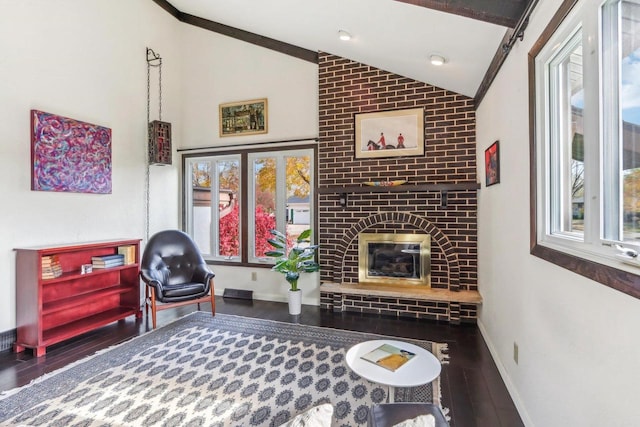 living area with dark wood-type flooring, vaulted ceiling, a fireplace, and plenty of natural light