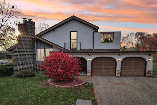 5302 Arapahoe Ln, Madison, WI 53704 - view of front of house with a balcony, a front yard, stucco siding, a chimney, and an attached garage