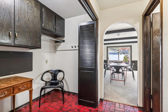 kitchen featuring dark brown cabinetry and dark colored carpet