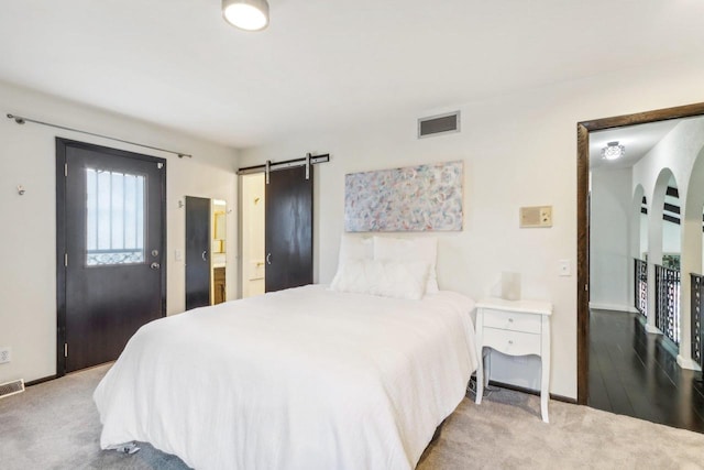 carpeted bedroom featuring a barn door