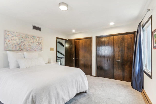 carpeted bedroom with multiple windows, multiple closets, and a baseboard radiator