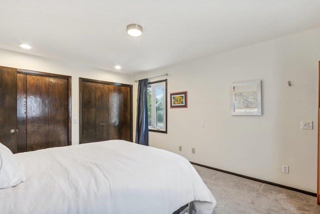 bedroom with light colored carpet and two closets