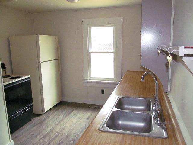 kitchen with light hardwood / wood-style floors, electric range, a healthy amount of sunlight, and sink