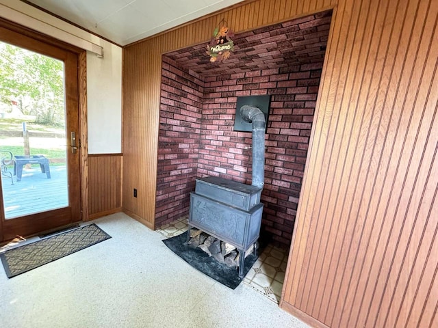 interior space featuring a wood stove, wood walls, and brick wall