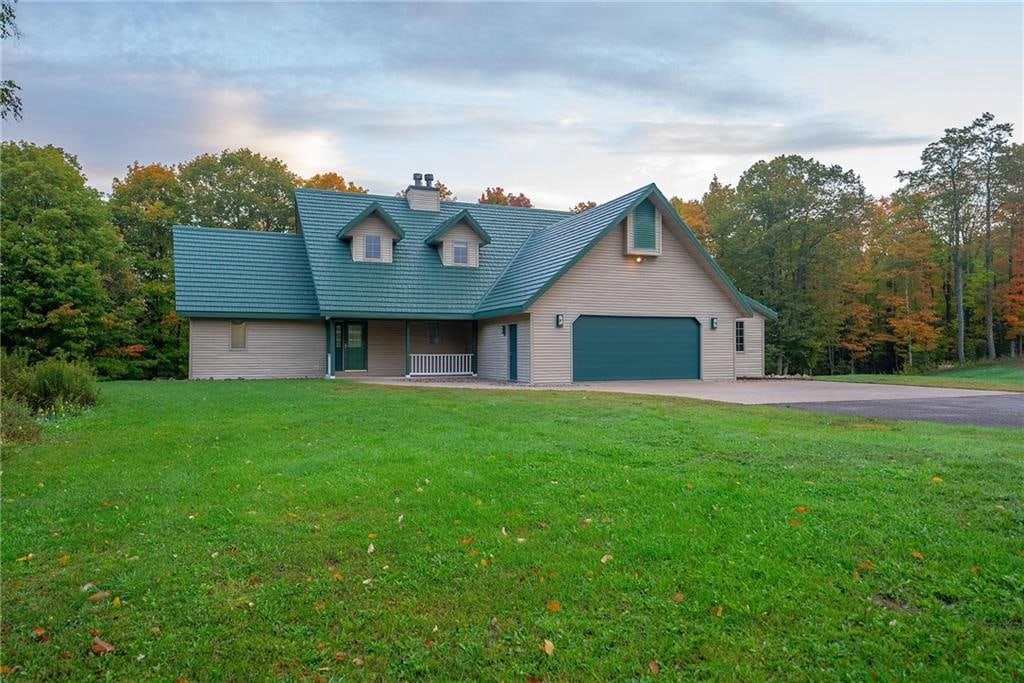 cape cod home featuring a garage and a front lawn