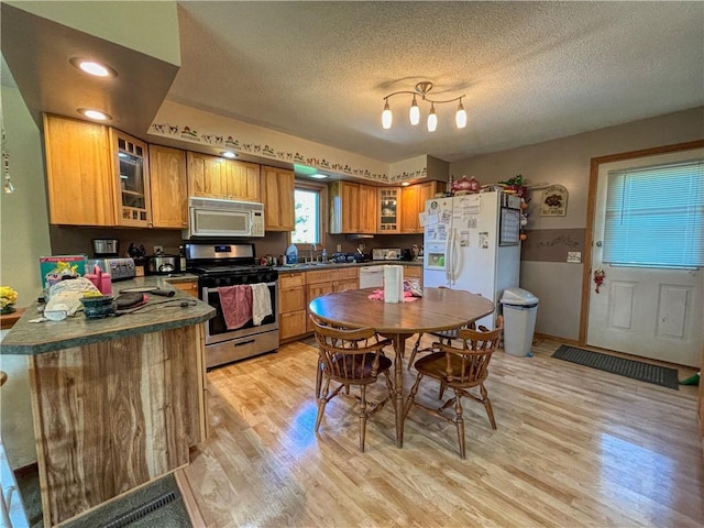 kitchen with a textured ceiling, white appliances, and light hardwood / wood-style floors