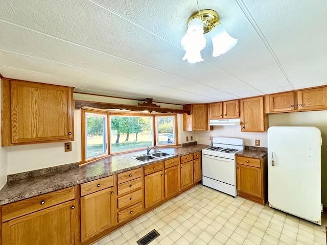 kitchen featuring ceiling fan, a textured ceiling, sink, and white appliances