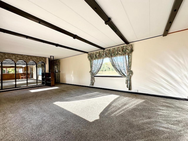 carpeted empty room with beamed ceiling