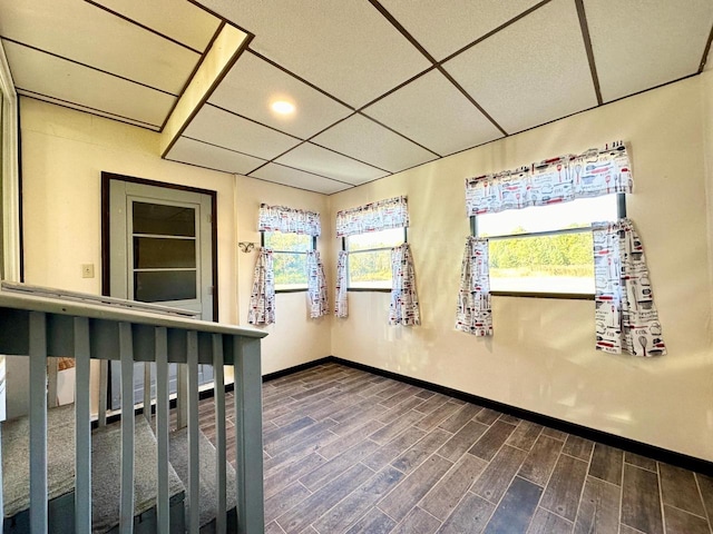 interior space with a drop ceiling and dark hardwood / wood-style flooring