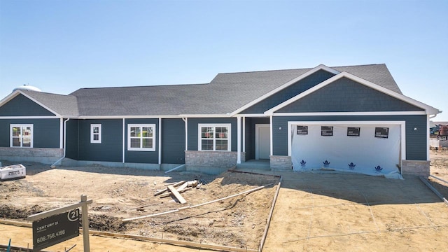 ranch-style home featuring stone siding and a shingled roof