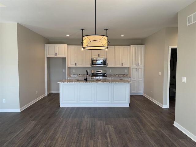 kitchen featuring light stone counters, an island with sink, dark hardwood / wood-style flooring, stainless steel appliances, and decorative light fixtures