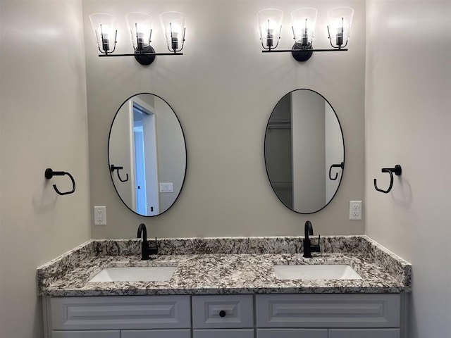 full bath with double vanity, a sink, and a notable chandelier