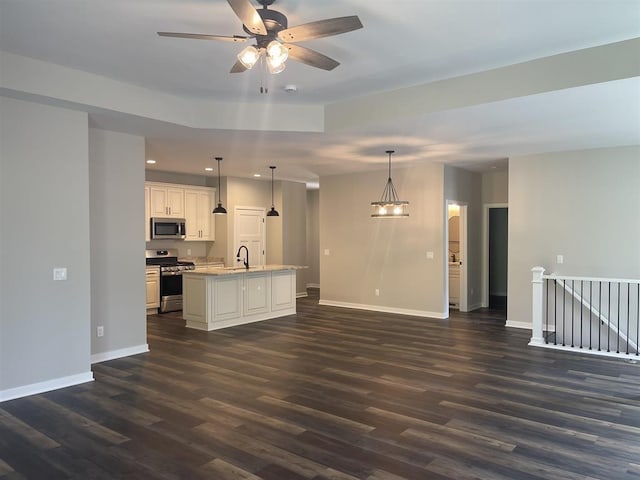 kitchen with baseboards, dark wood finished floors, a sink, stainless steel appliances, and open floor plan