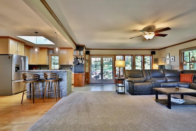 living room with a healthy amount of sunlight, crown molding, ceiling fan, and a skylight