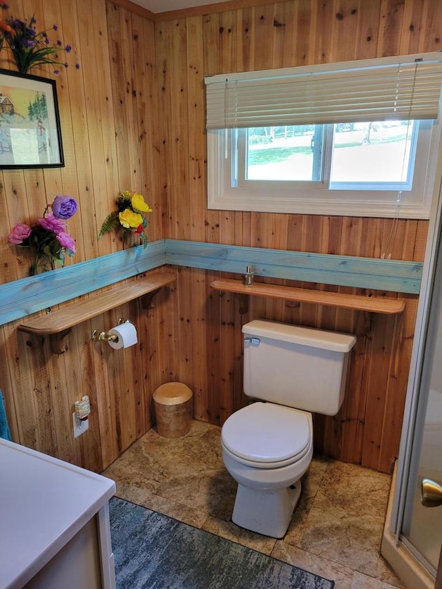 bathroom featuring wood walls, a shower with door, a healthy amount of sunlight, and toilet