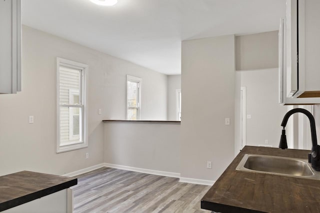 kitchen with butcher block countertops, sink, and light hardwood / wood-style flooring