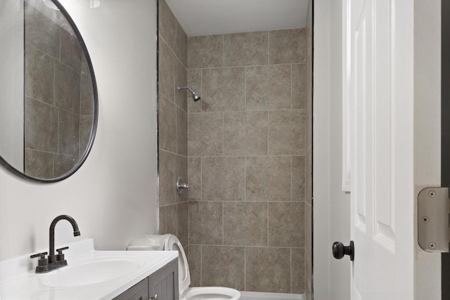 bathroom featuring a tile shower, vanity, and toilet