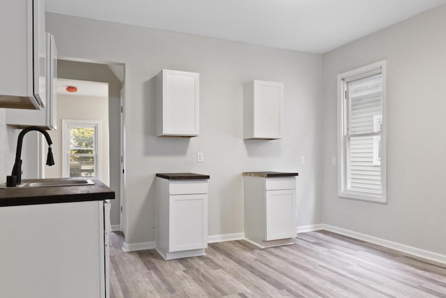 interior space featuring light wood-type flooring, white cabinets, and sink