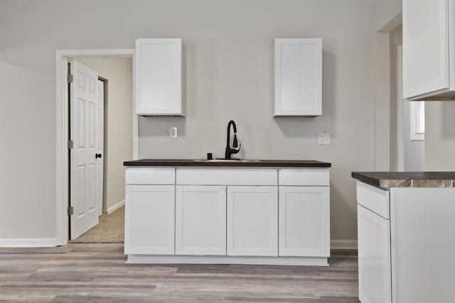 kitchen featuring light hardwood / wood-style floors, white cabinetry, and sink