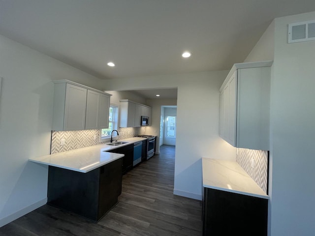 kitchen with white cabinets, sink, backsplash, stainless steel appliances, and dark hardwood / wood-style floors