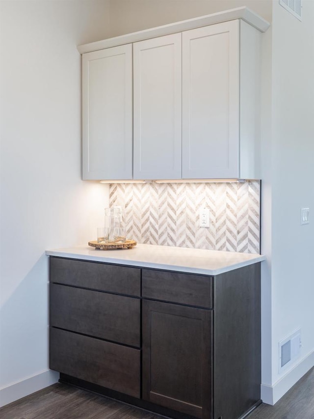 1295 Stonehaven Dr, Sun Prairie, WI 53590 - bar featuring dark wood-style flooring, visible vents, baseboards, and decorative backsplash