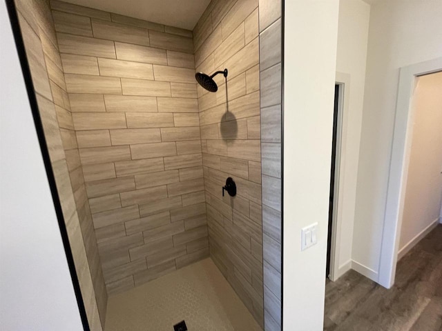 bathroom with wood-type flooring and a tile shower