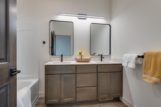 1295 Stonehaven Dr, Sun Prairie, WI 53590 - bathroom featuring a sink, a tub to relax in, double vanity, and wood finished floors