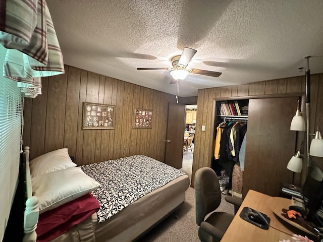 carpeted bedroom featuring wood walls, a closet, ceiling fan, and a textured ceiling