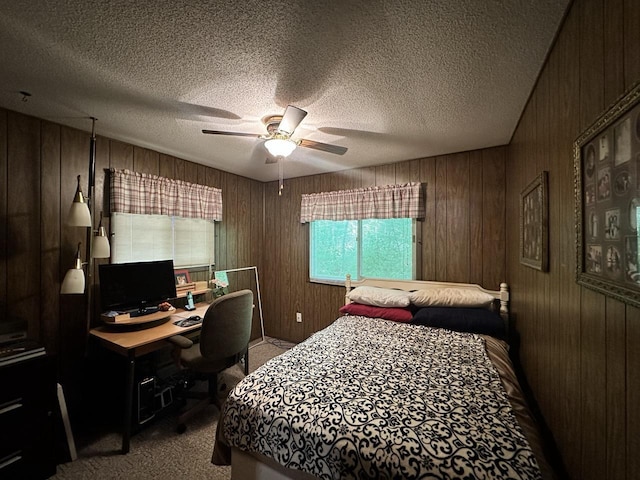 bedroom with ceiling fan, a textured ceiling, light carpet, and wood walls