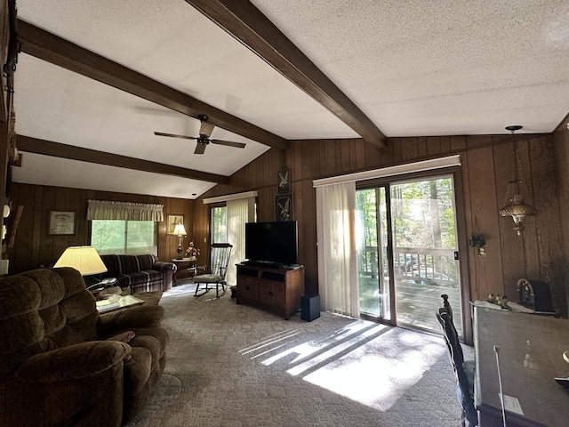 living room with carpet, wood walls, lofted ceiling with beams, and ceiling fan