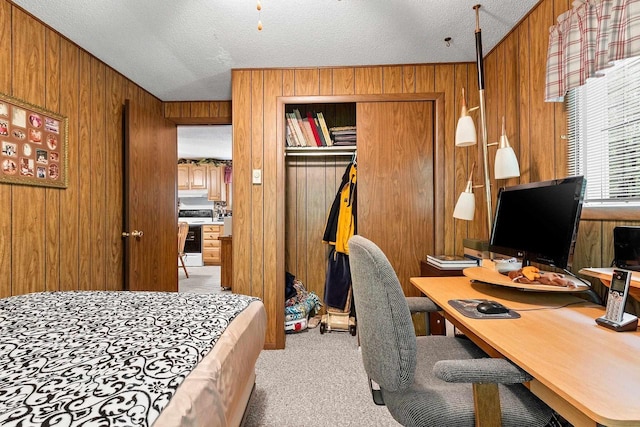 carpeted office featuring a textured ceiling and wooden walls