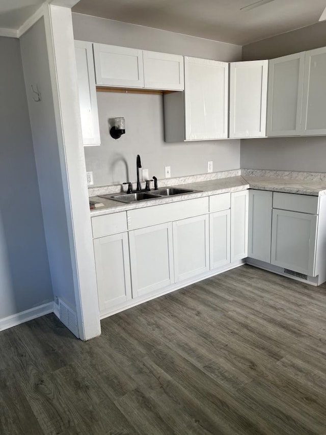 kitchen featuring dark hardwood / wood-style floors, crown molding, white cabinetry, and sink