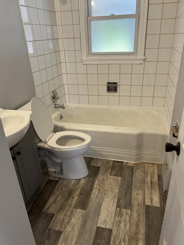 full bathroom with wood-type flooring, tiled shower / bath, vanity, and toilet