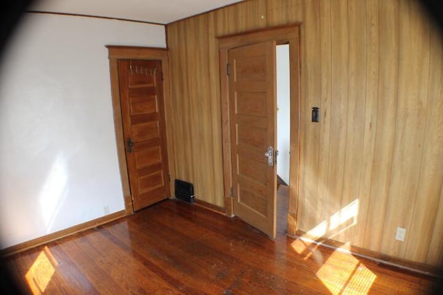 unfurnished room featuring wood walls and dark hardwood / wood-style flooring