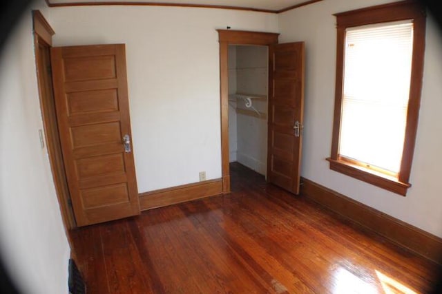 unfurnished bedroom featuring dark wood-type flooring and crown molding