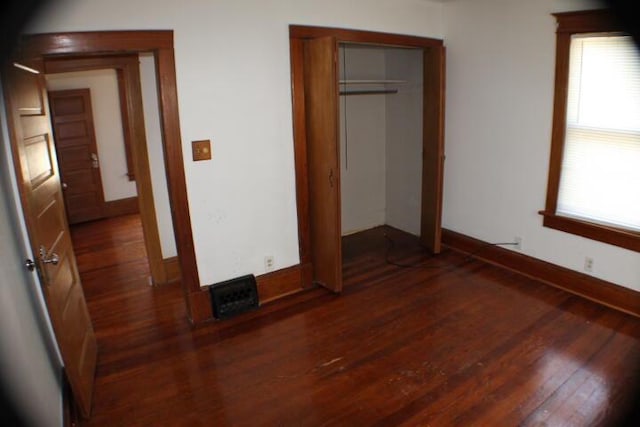 unfurnished bedroom featuring a closet and dark hardwood / wood-style floors