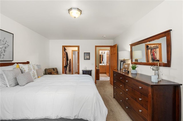 bedroom with light colored carpet, a closet, connected bathroom, and a walk in closet