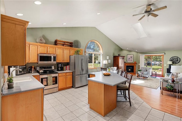 kitchen featuring a wealth of natural light, appliances with stainless steel finishes, a kitchen island, and a breakfast bar area