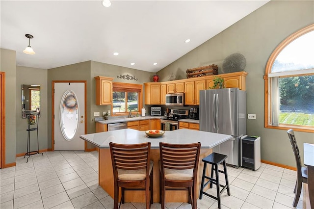 kitchen with stainless steel appliances, a center island, a kitchen bar, and sink