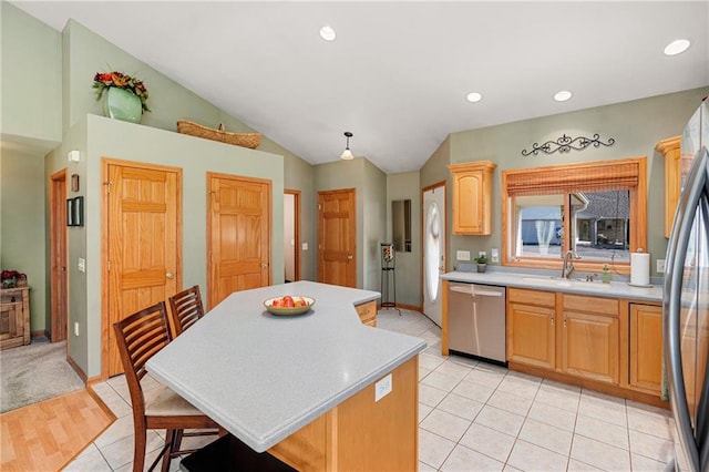 kitchen with light tile patterned flooring, lofted ceiling, sink, a kitchen island, and appliances with stainless steel finishes