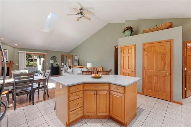 kitchen featuring light tile patterned floors, lofted ceiling with skylight, a center island, and ceiling fan