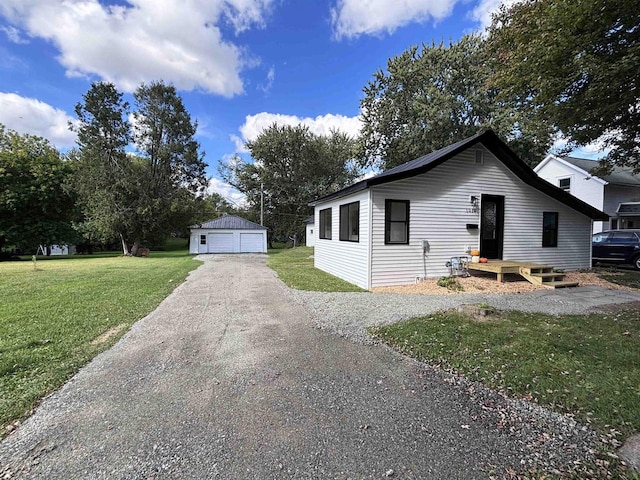 view of front of home with a front yard, a garage, and an outbuilding