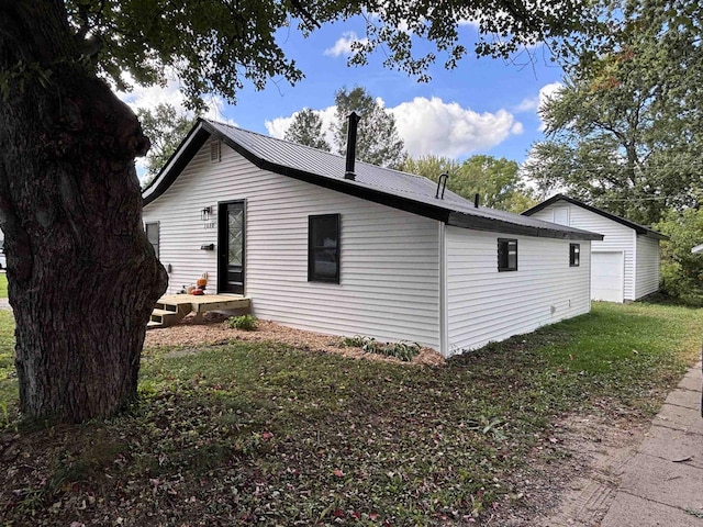 view of property exterior with a yard, an outbuilding, and a garage